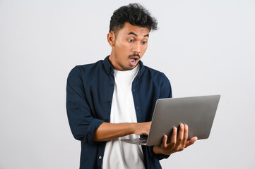 Portrait of shocked asian businessman working on laptop computer isolated over white background