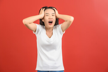 Portrait of Attractive shocked young asian woman in white t-shirt standing isolated on red background