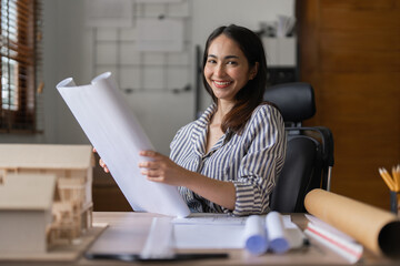 Architect woman working with blueprints for architectural plan, engineer sketching a construction project, green energy concept