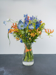 An unusual orange-purple bouquet of flowers with Nigella flowers. Bouquet of flowers in a glass vase. A florist's fantasy.