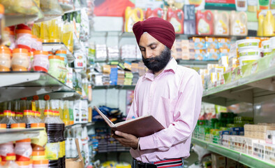 Indian sales man Making list on notebook in grocery store