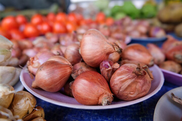Plates of neatly organised fruit and vegetables including shallot onions at local market stall on tropical island of Timor Leste in Southeast Asia