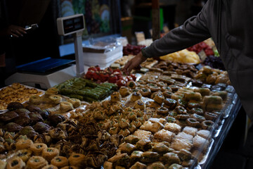 A man chooses oriental sweets in the bazaar. Stall with lots of dessert selection.