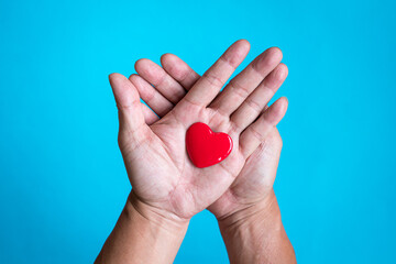 Heart health concept. Red heart shape on the palm of hand. Top view.