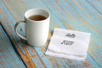 Hello 2023 on white napkin, next to a cup of coffee. Welcome new year concept.