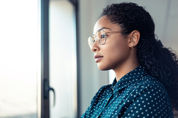 Beautiful businesswoman taking a break while looking forwards to the window at the office.