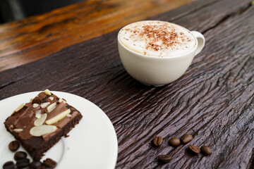 Hot cappuccino in white cup with wooden background,coffee is a popular drink all over the world.