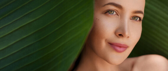 Green beauty portrait. Organic cosmetic concept. Beautiful young woman posing against and behind...