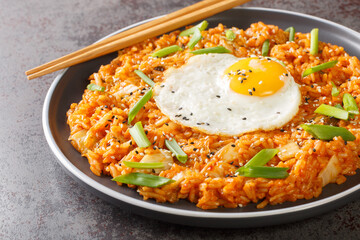 Homemade kimchi fried rice topped with fried egg closeup on the plate on the table. Horizontal