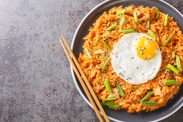 Kimchi fried rice with fried egg on top and chopsticks for eating Korean food closeup on the plate...