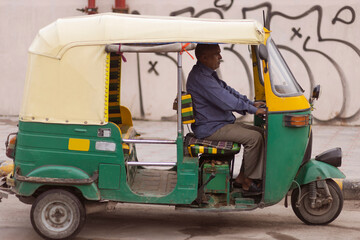 middle-aged man driving auto rickshaw on street