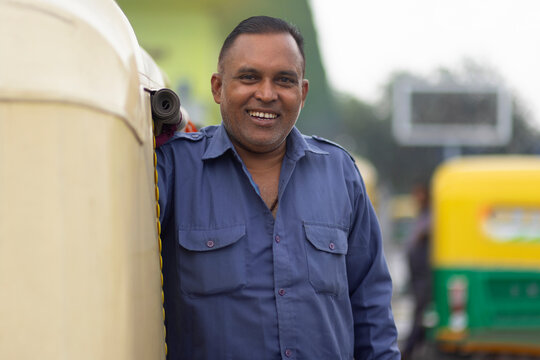 Portrait of a smiling auto rickshaw driver standing in auto stand