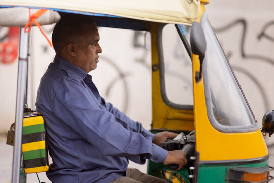 Portrait of middle-aged man driving auto rickshaw