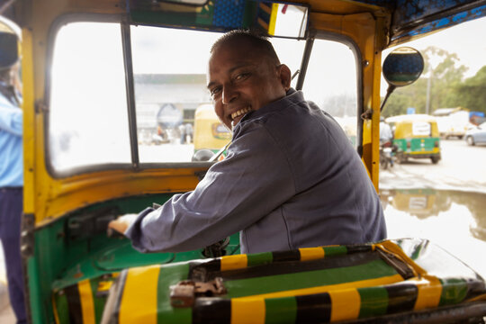 Portrait of an auto rickshaw driver looking back while driving