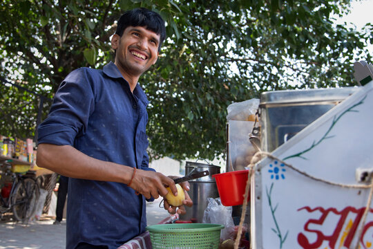 Portrait of a smiling male vendor peeling off potato