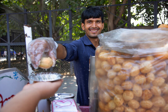Portrait of a happy young male vendor selling panipuri 