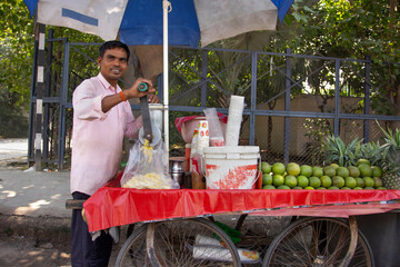 Male street vendor making fruit juice at his juice shop