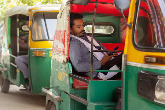 Auto rickshaw drivers using mobile phone while sitting inside