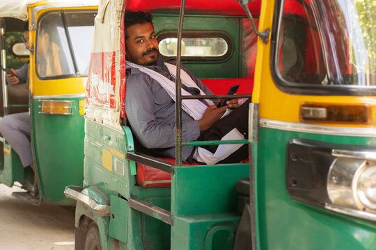 Auto rickshaw driver using mobile phone while sitting inside
