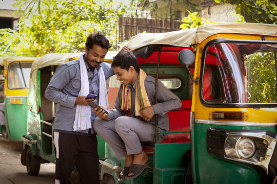 Auto rickshaw drivers using their mobile phones at auto stand
