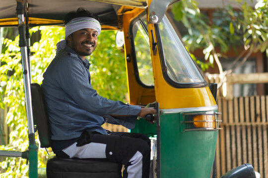 Portrait of a happy young man driving auto rickshaw
