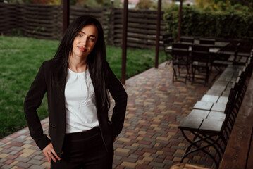 beautiful girl with black hair dressed in a black business suit on the street