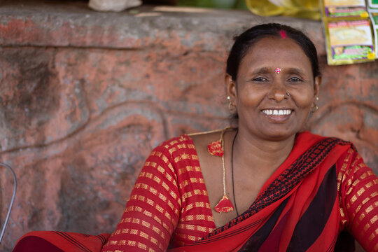 Portrait of a smiling female tea vendor sitting at a roadside stall