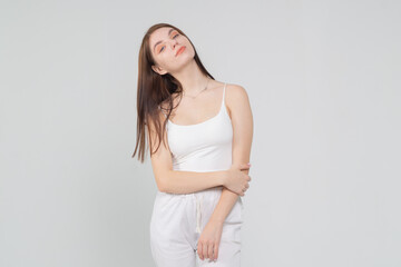 Half-length portrait of a beautiful young brown-haired girl in a white top and trousers on a white background