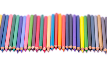 Multi-colored pencils, arranged, sharpened, on a white background, blurry background.