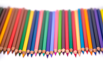 colors pencils arranged in a clear  blurred background on a white background.