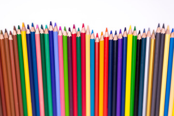 Multi-colored pencils arranged vertically top corner  white background
