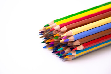 pencils of many colors close-up grouped together laid on a white background