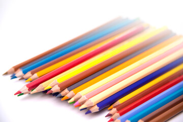 Colors pencils of many colors arranged in a row on a white background 