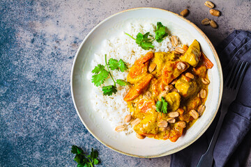Thai chicken and peanut curry with rice in gray bowl, dark background.