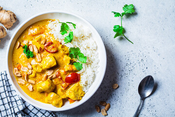 Thai chicken and peanut curry with rice in white bowl, gray background. Asian cuisine concept. - obrazy, fototapety, plakaty