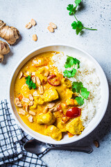 Thai chicken and peanut curry with rice in white bowl, gray background. Asian cuisine concept. - obrazy, fototapety, plakaty