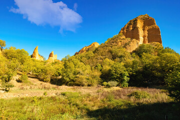 Beautiful cliffs of reddish clay color combine with the forests of chestnut trees, oaks, holm oaks of the natural park of La Médulas, Castilla y Léon, Spain