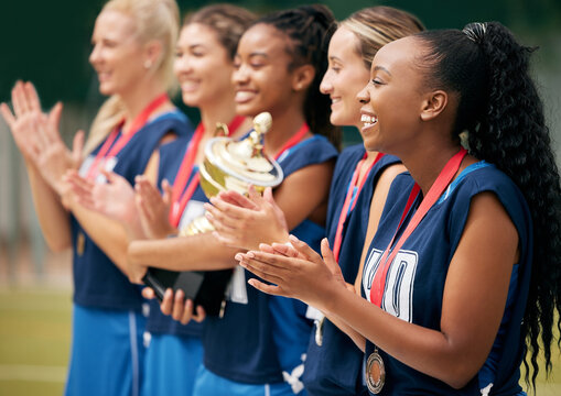 Trophy, sports and women clapping hands for success, motivation or celebration at professional netball game. Winning, support and athlete team with trust, support and smile to celebrate win in sport