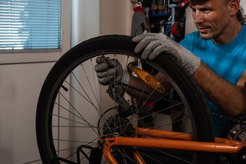 Fototapeta na wymiar Concentrated cycling mechanic checking bicycle wheel spoke