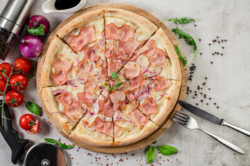 Fresh pizza with meat and ham on the concrete background