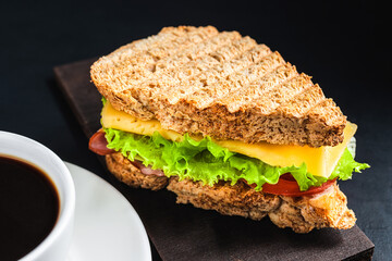 Grilled sandwich with a cheese, salad lettuce, ham on dark background. Lunch concept