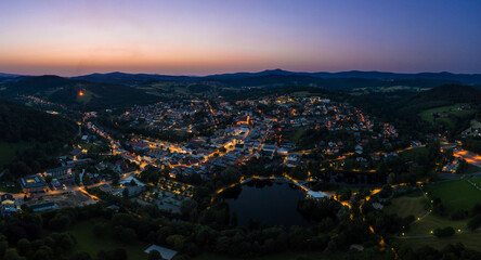 Luftaufnahme mit einer Drohne der Stadt Grafenau im bayerischen Wald zur Sommersonnenwende und Johannifeuer bei Sonnenuntergang zur blauen Stunde im Zwielicht, Deutschland