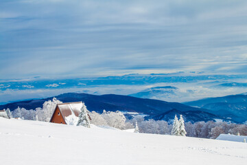 Isolated a-frame mountain house (shelter) surrounded with trees covered with snow in winter with beautiful view 