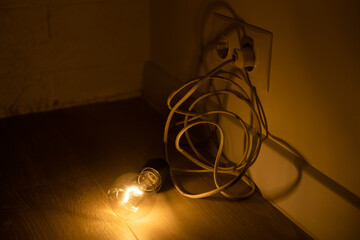 Single lightbulb hanging from a wire in a dark room with a warm glow.