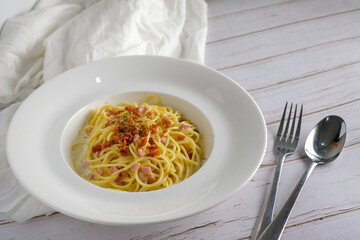 Spaghetti carbonara with bacon on white dish.