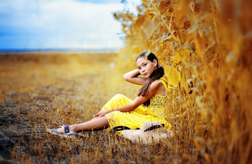 A beautiful girl walks in a sunflower field. A sunny field and a girl.