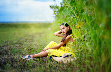 A beautiful girl walks in a sunflower field. A sunny field and a girl.