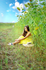 A beautiful girl walks in a sunflower field. A sunny field and a girl.