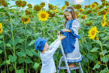 two children in a sunflower field.a boy and a girl collect sunflower seeds from a sunflower