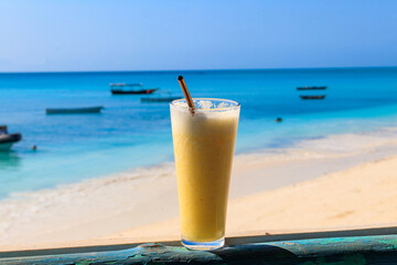 Glass of fresh juice by the ocean. Tropical vacations concept